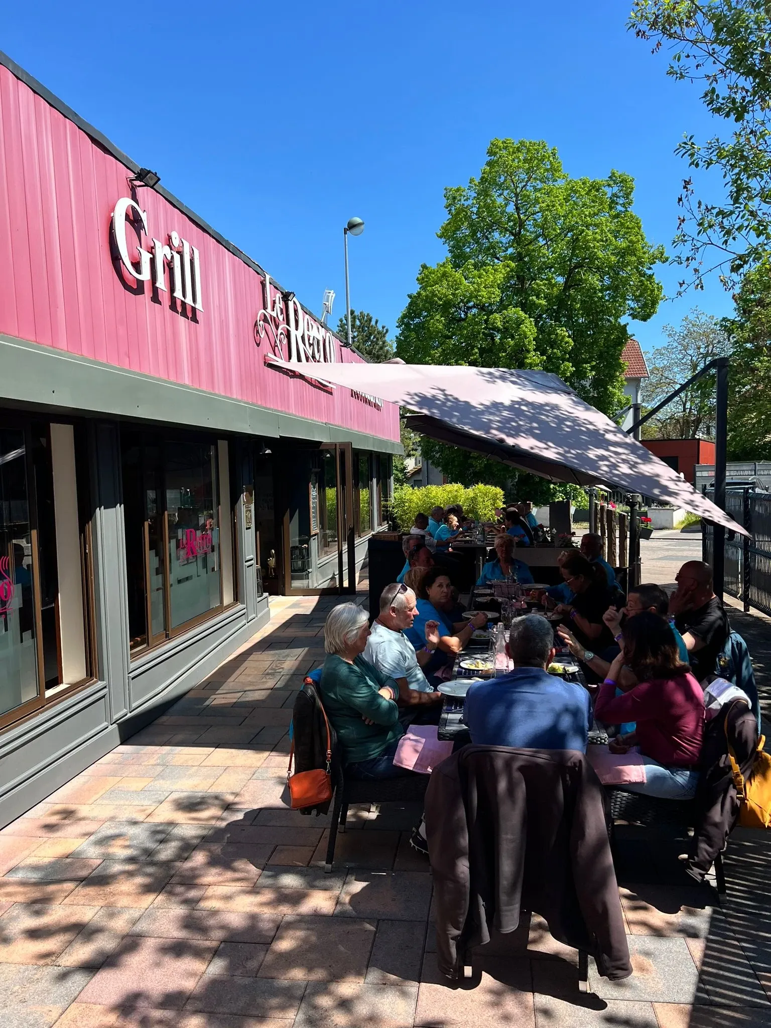 Des clients déjeunent sur la terrasse ombragée du Rétro